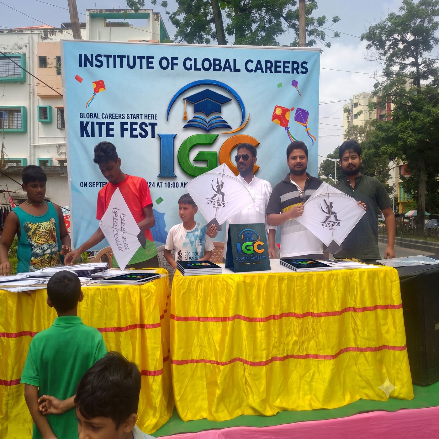 IGC Kite Fest banner and volunteers with children holding kites